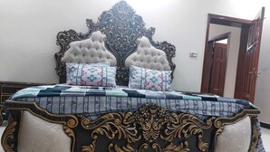A bed with an ornate headboard, a quilted bedspread, and two decorative pillows. - Beautiful 3-bed House in Islamabad (Rawalpindi)