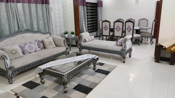 A living room with two sofas, a coffee table, and a dining area with chairs and a table. - Beautiful 3-bed House in Islamabad (Rawalpindi)