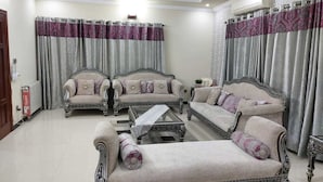 A living room with two sofas, a coffee table, and curtains. - Beautiful 3-bed House in Islamabad (Rawalpindi)
