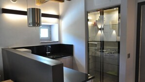 Una cocina moderna con encimera negra, electrodomésticos de acero inoxidable y un refrigerador con puerta de vidrio.