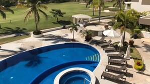 A swimming pool with lounge chairs and a view of a golf course. - Condos SB (Mazatlán)