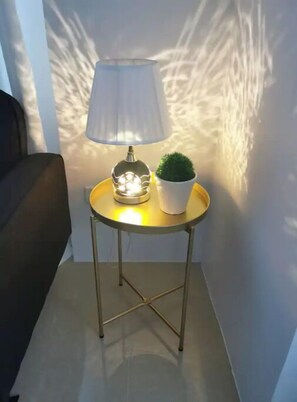 A small round table with a lamp and a potted plant. - Hidden Gem, IG-worthy 1BR near GMA-MRTqc, FastWifi (Quezon City)