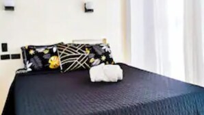 Una habitación de hotel con una cama, aire acondicionado en la pared y una ventana con cortinas.
