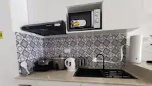 Una pequeña cocina americana equipada con microondas, hervidor y tostadora.