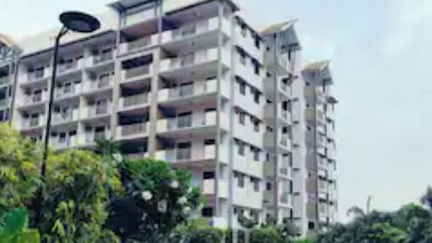 Un edificio residencial de varios pisos con balcones, piscina y follaje circundante.