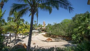 Un resort tropical con palmeras, una playa arenosa y una fuente de agua.