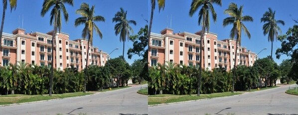 A hotel with a symmetrical facade, multiple floors, and a central courtyard with palm trees. - Condos Marina CB (Mazatlán)