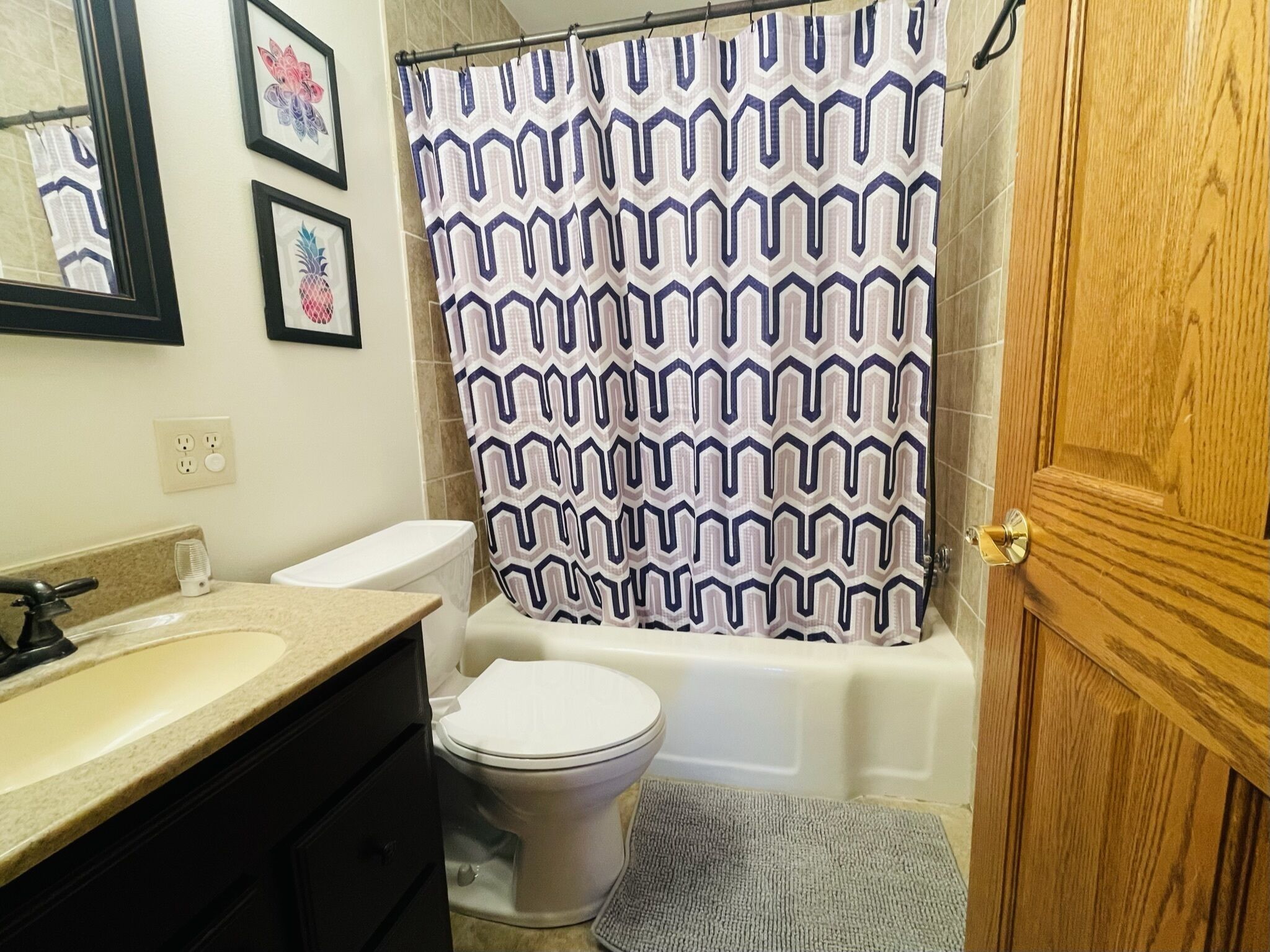 A bathroom with a shower curtain, toilet, sink, and a wooden door.
