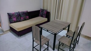 Un petit salon avec un canapé et une table à manger entourée de quatre chaises.