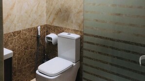 Une salle de bain équipée de toilettes, d’un sèche-mains et d’une cabine de douche en verre.