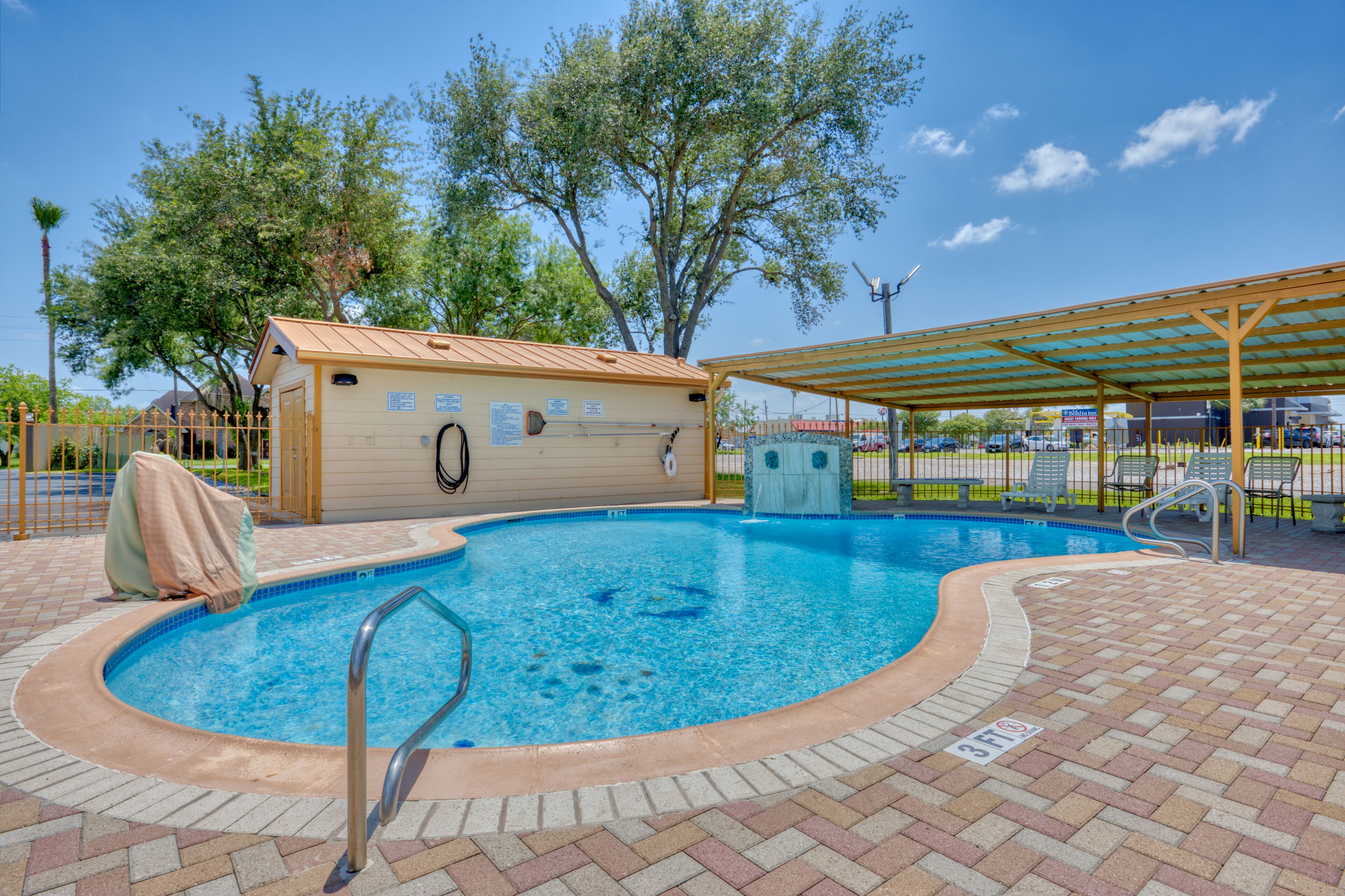 A swimming pool with a covered area, a lifeguard chair, and a lifebuoy.