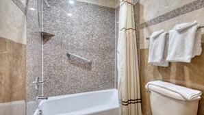 Een badkamer met bad, douche en toilet.