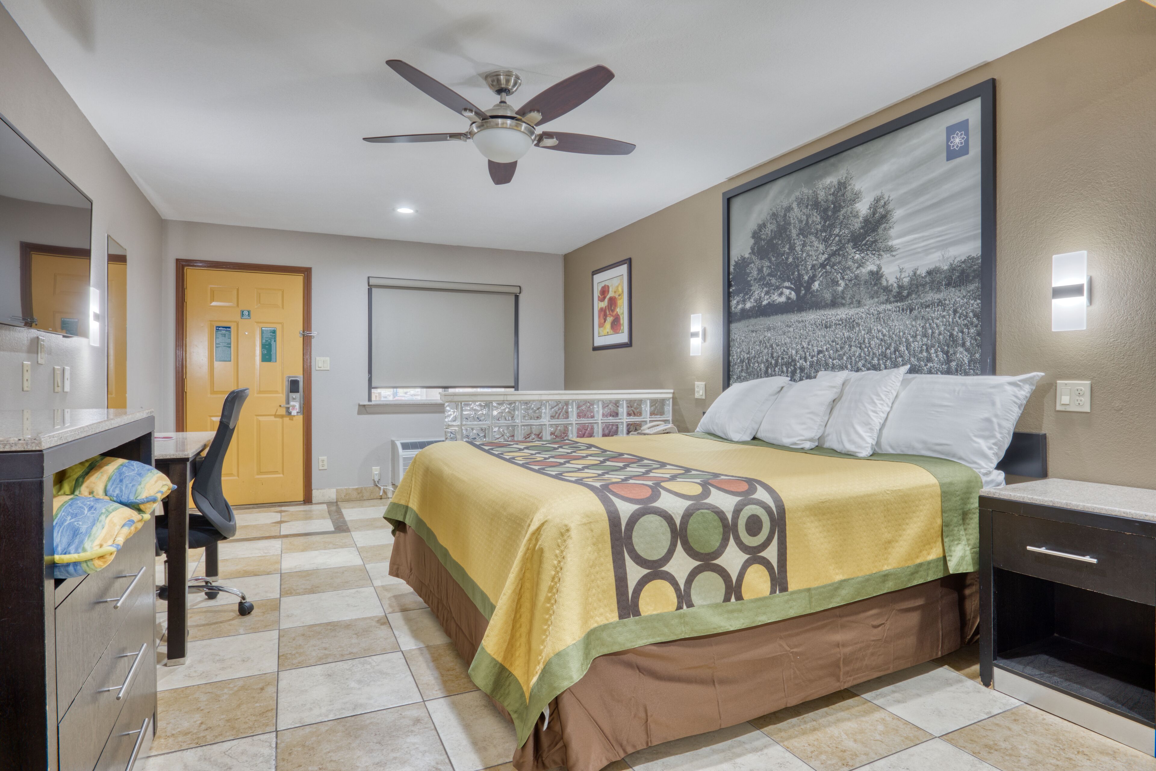 Une chambre d’hôtel équipée d’un lit, d’un bureau, d’une chaise et d’un ventilateur de plafond.
