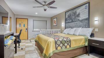 Une chambre d’hôtel équipée d’un lit, d’un bureau, d’une chaise et d’un ventilateur de plafond.