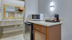 Een kleine kitchenette met een magnetron, koffiezetapparaat en een koelkastje.