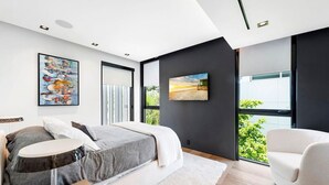 A modern bedroom with a bed, a chair, and artwork on the walls. - Playa Villa - Modern Luxury Redefined (Miami Beach)