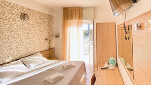 Habitación de hotel con cama, escritorio, espejo y vistas al exterior.