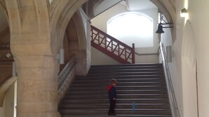 Un escalier avec des marches en pierre et des rampes en bois, menant à un niveau supérieur.