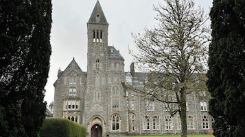 A stone building with a tower, steps leading to the entrance, and a well-maintained lawn.
