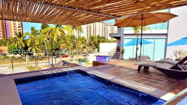 An indoor swimming pool with a wooden deck and lounge chairs. - Depas Manzara (Mazatlán)