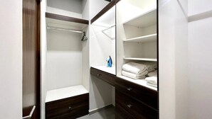 A walk-in closet with open shelves, a hanging rod, and a folded towel rack. - Depas Manzara (Mazatlán)
