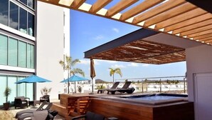 A rooftop pool area with lounge chairs and umbrellas, a hot tub, and a view of the cityscape. - Depas Manzara (Mazatlán)
