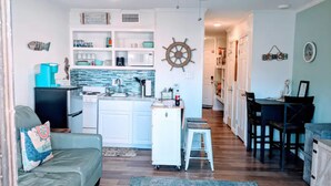 A compact kitchen with white cabinets, a central island, and a small refrigerator.