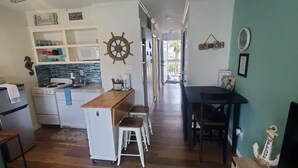 A spacious kitchen with a wooden dining table and stools, a microwave, and a small refrigerator.