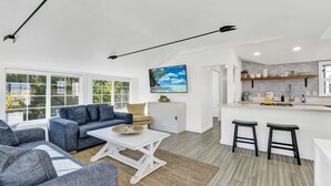 A modern living room with a sofa, a coffee table, and a kitchen area with a bar. - Modern A-Frame | Walkable | Two Balconies | Views (Avalon)