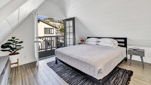 A bedroom with a bed, a nightstand, a potted plant, and a view of the outside. - Modern A-Frame | Walkable | Two Balconies | Views (Avalon)