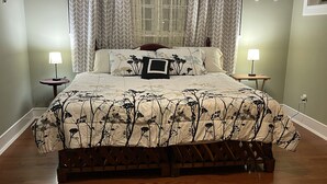 Een slaapkamer met een bed, twee nachtkastjes, een plafondventilator en een raam met gordijnen.