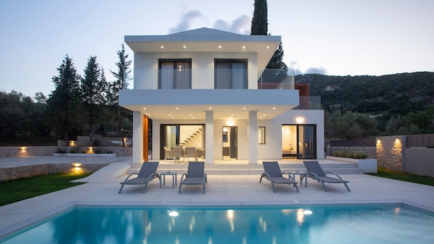 Una casa moderna de dos pisos con piscina, mobiliario exterior y una escalera que lleva al nivel superior.