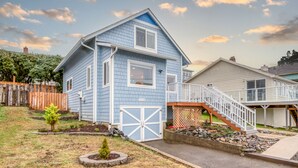 A two-story house with a blue exterior, a white garage door, and a front porch with a staircase. - Steps to the beach, ocean view, deck, BBQ, pet friendly with a fenced in yard (Lincoln City)