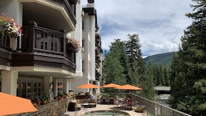 Un espace piscine équipé de chaises longues, de parasols et offrant une vue sur une chaîne de montagnes boisées.