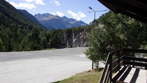 Ein asphaltierter Weg führt zu einem Berggebiet mit einer Bank und einer Straßenlaterne.