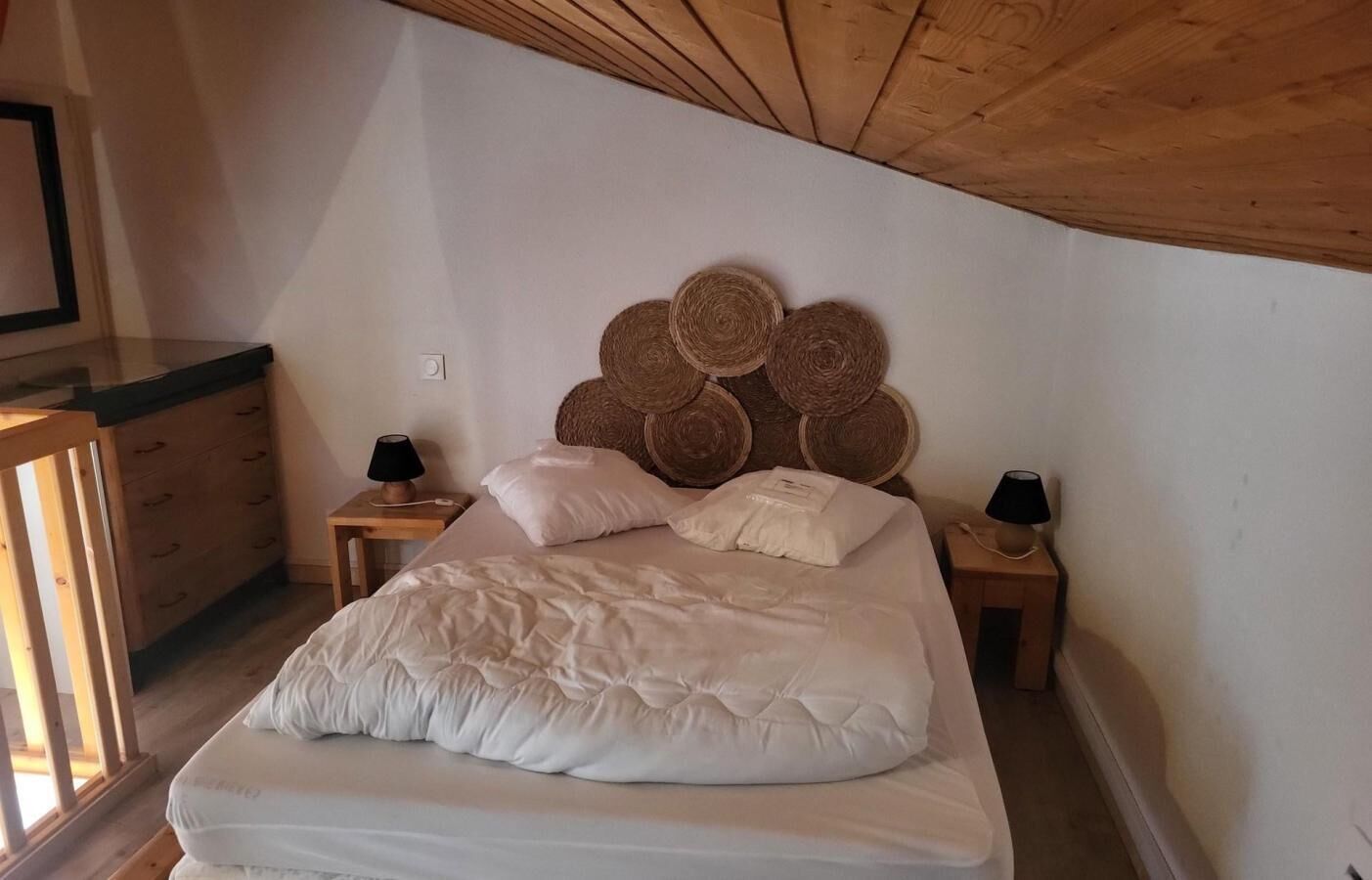 Ein Schlafzimmer mit einem Bett, zwei Nachttischen, einem Holzkopfteil mit gewebten Körben und einer Holzkommode.
