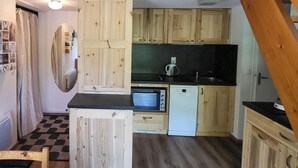 Eine kleine Küche mit Holzschränken, einer Mikrowelle und einem Geschirrspüler.