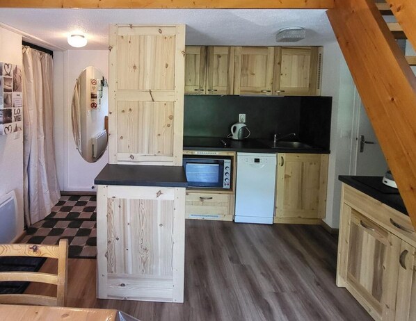 Una cocina compacta con armarios de madera, un microondas y un lavavajillas.