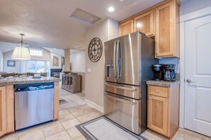 A modern kitchen with stainless steel appliances, wooden cabinets, and a large clock on the wall. - Walk to Beach or Town, Enjoy Balcony Views and Feel the Ocean Breeze (Rockaway Beach)
