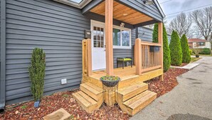 Una casa con un porche cubierto, una pequeña terraza y una puerta principal.