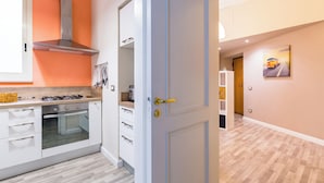 Une cuisine moderne avec des armoires blanches, une hotte de cuisinière en acier inoxydable et un four encastré.