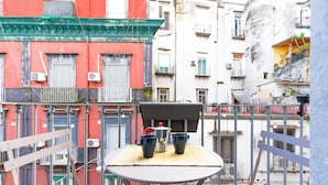 Un balcon avec une table, deux tasses et un pot.