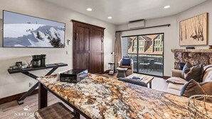 A spacious living room with a large TV, a fireplace, and a view of the outside.