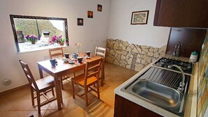 Een keuken met een stenen muur, een gootsteen en een raam met uitzicht op een tuin.