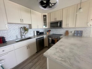 A modern kitchen with white cabinetry, a stainless steel stove, a microwave, and a dishwasher.