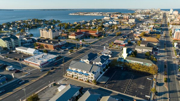 An aerial view of a coastal town with a marina, wide streets, and various buildings including a hotel with a prominent red roof.