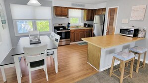 Eine moderne Küche mit Holdekor, einem Edelstahl-Kühlschrank, einem Einbauofen und einer Holzinsel mit Barhocker.