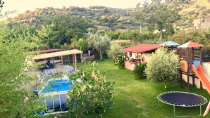 A backyard with a trampoline, a pool, and a covered patio area.