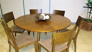 Una mesa de comedor redonda de madera con seis sillas, cada una con un cojín a rayas.