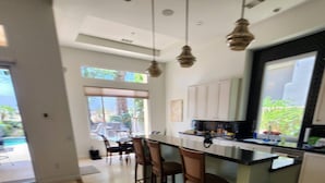 Una cocina moderna con una isla central, taburetes de bar e iluminación colgante.